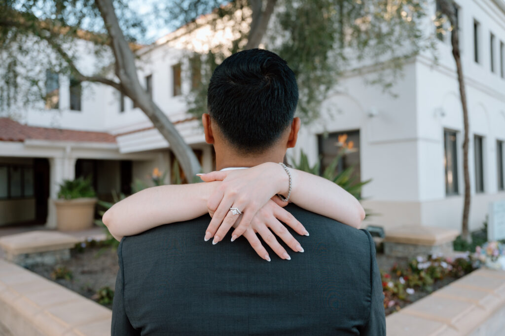 A bride's arms around a groom showcasing her ring at Laguna Hills Civic Center